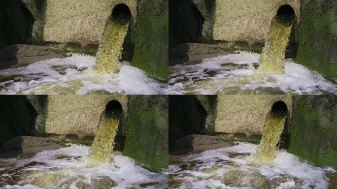 瀑布从布满青苔的岩壁上的管道中冒出来。缓慢的运动。缩小