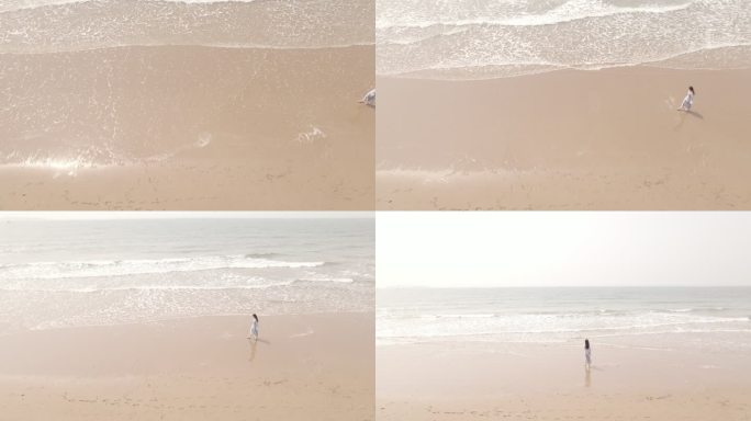 俯拍伴随着海浪女子走在沙滩上