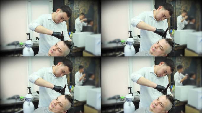 在理发店里，一位戴着黑色手套的理发师用直刀给顾客刮胡子。中景镜头。