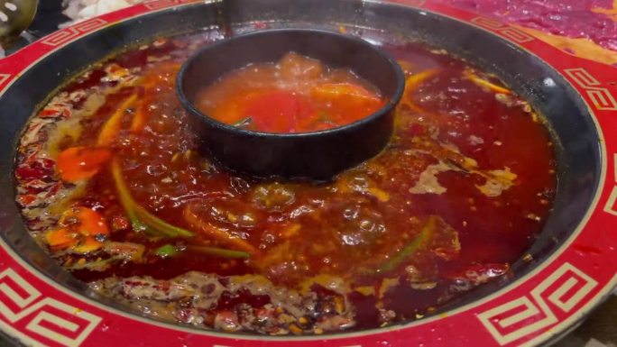 热腾腾的两味四川火锅配辣味番茄汤，筷子滴入牛肉、香菇、鲜牛肚和虾饺