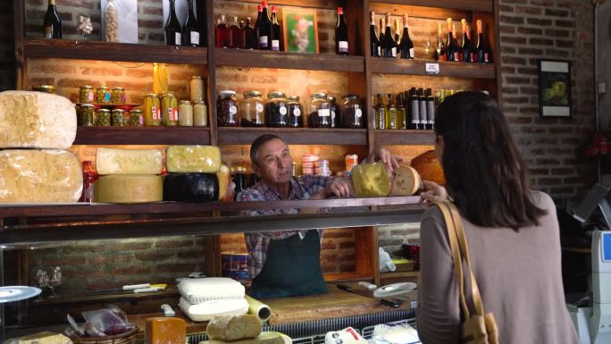 熟食店的老老板向一位不认识的女顾客推荐一种特别的奶酪