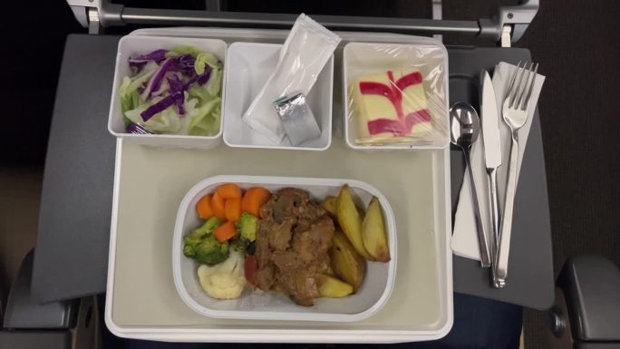 经济舱基本餐食的俯视图，包括土豆、牛肉和沙拉。

经济舱的托盘里有食物。