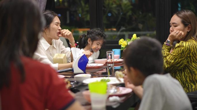 穿白衬衫的女人和家人一起吃饭时牙痛。