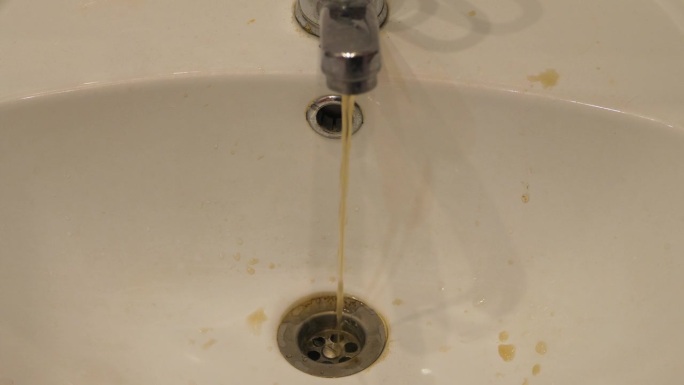 生锈的脏水从水龙头流入家里的水槽。淡水污染问题，供水故障