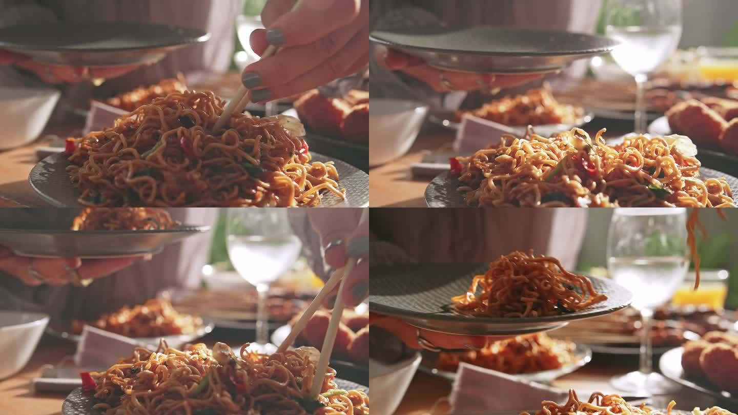 餐桌上的新鲜亚洲美食。以东方产品为原料的亚洲烹饪配方概念。对妇女用竹签手拿植物油炒面的看法