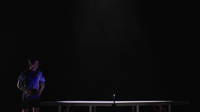 男子乒乓球运动员站在乒乓球桌前看向对手