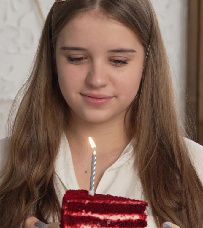 竖屏:生日女孩在工作室里吹灭蛋糕上的蜡烛，背景是一个气球。一个快乐的女人庆祝一个特殊的日子或事件的脸