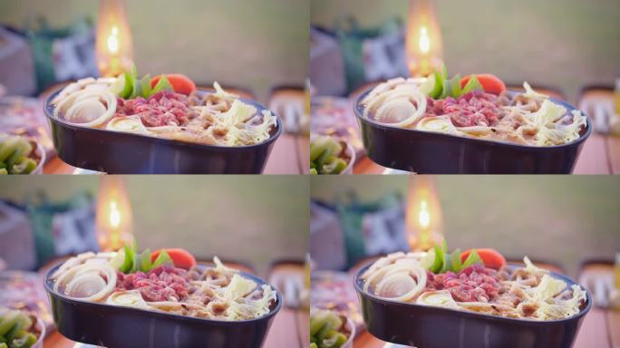 户外火锅用餐体验，新鲜蔬菜和切成薄片的牛肉，在露营灯的照亮下