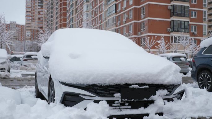 院子里停着一辆没有牌照、被雪覆盖的汽车的特写。