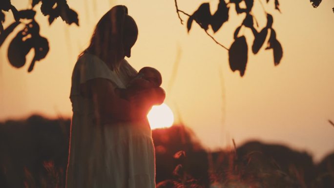 黄昏时分，站在橙色天空的球场上，慈爱的母亲亲吻小男孩的SLO手持镜头