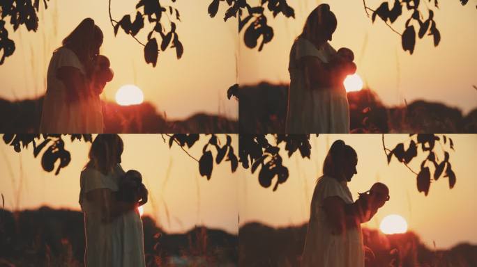 黄昏时分，站在橙色天空的球场上，慈爱的母亲亲吻小男孩的SLO手持镜头
