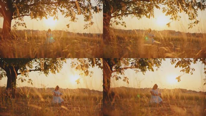 在明亮的夕阳天空下，跪在田野上的母亲抱着孩子在大树枝下的慢镜头