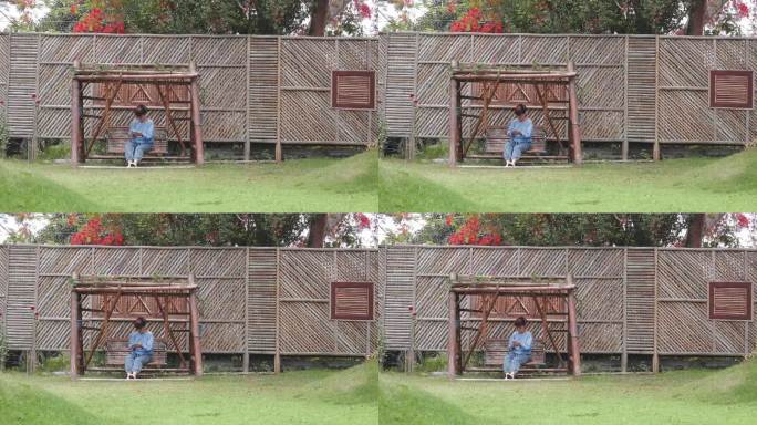 一位年长的女士坐在秋千上放松地用她的手机看社交网络上的信息