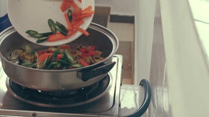 将切碎的胡萝卜和青椒加入炒笋或拉桶中，这是菲律宾当地的传统美食，展示了菲律宾的正宗美食和日常生活