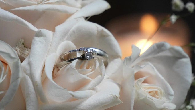 新娘捧花上的白玫瑰花瓣中间夹着两枚白金结婚戒指。婚礼的细节