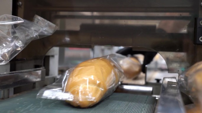 在面包包装生产线上，新鲜面包被透明包装薄膜包裹