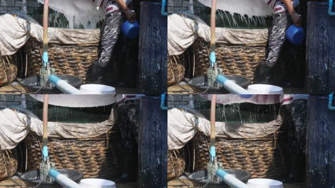 泡过的大米被磨成细粉，倒进塑料盆里做米粉。背景中，一名工人正在筛米粉，轻轻地拍着布。