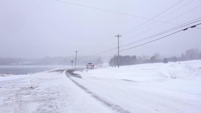 暴风雪中行驶在乡村道路上的汽车。危险的驾驶条件。