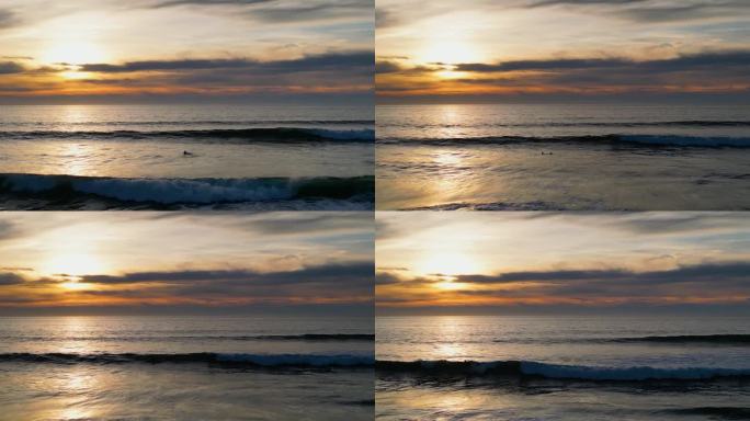 4K无人机拍摄的冲浪者在美丽的日落时捕捉海浪的画面。