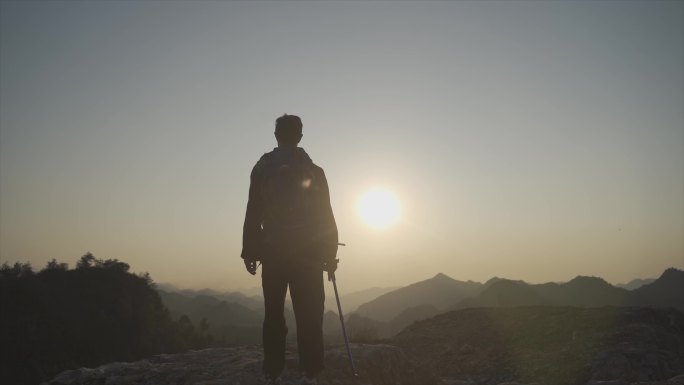 背着登山包男人山顶逆光行走背影走向山顶