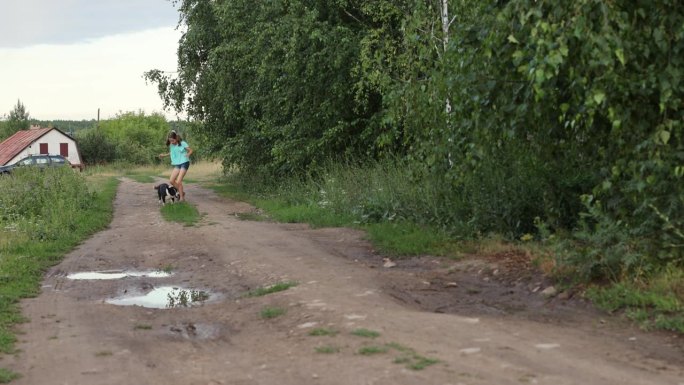 十几岁的女孩带着她的狗在村里跑来跑去，孩子和动物之间的友谊概念。