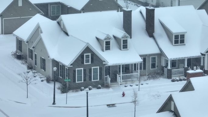 大雪覆盖了郊区的房屋和街道。空中视差拍摄的现代住宅在美国附近在暴风雪。