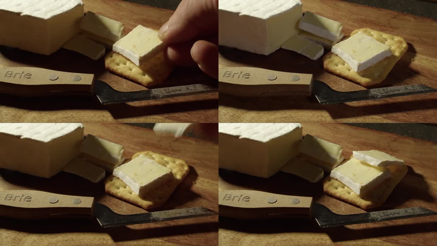 将切好的布里干酪片放在苏打饼干上，刀放在板上