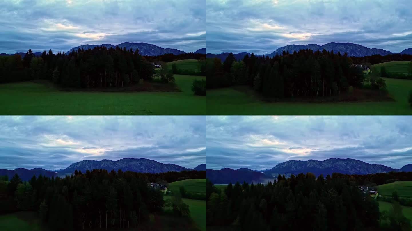 在奥地利的一个阴天，一架无人机在森林上空拍摄，背景是一个大湖。