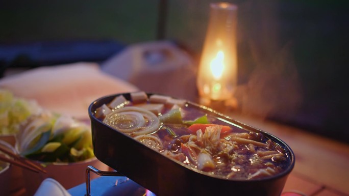 一个人用筷子享用美味火锅的特写，背景是温暖的烛光