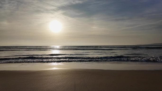 海浪翻滚到沙滩上，背景是蓝天，戏剧性的雷云，日落，美丽的风景，慢动作