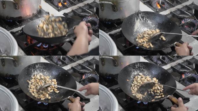 厨师在商业厨房用大火炒锅炒贻贝，动作镜头