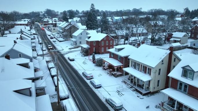 白雪覆盖的街道上有古色古香的雪屋。冬季美国城镇的空中飞行。东北部居民区降雪。