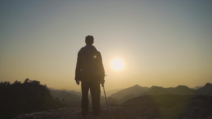 背着登山包男人山顶逆光行走背影走向山顶