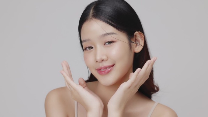 肖像美丽的年轻亚洲女性与健康的面部皮肤轻轻触摸脸。