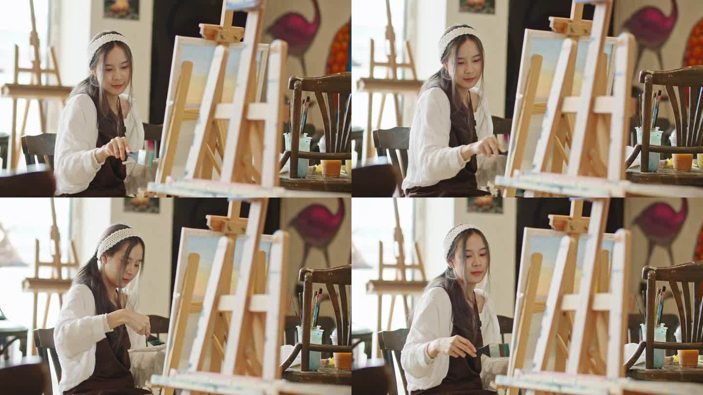 年轻的亚洲女艺术家在艺术工作室画日落风景画。