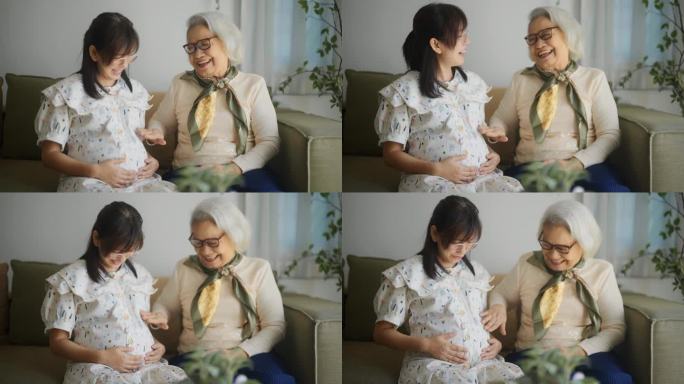 一位老妇人亲切地说着话，在家里抚摸着她怀孕的女儿的肚子。