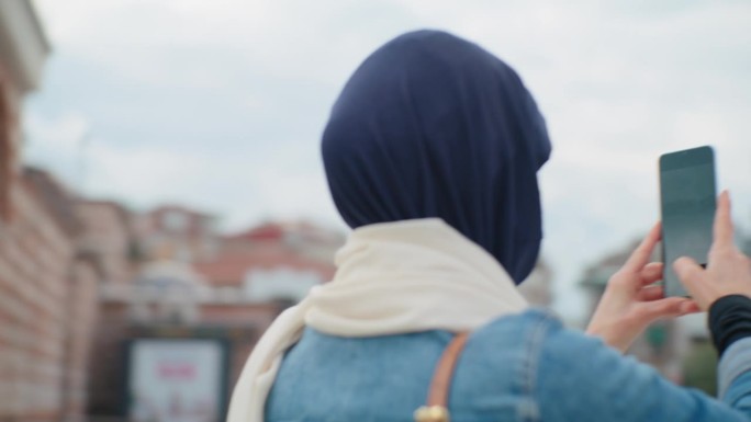 一位女游客用她的智能手机在伊斯坦布尔的清真寺拍照#清真寺连接#数字沉思#伊斯兰反思