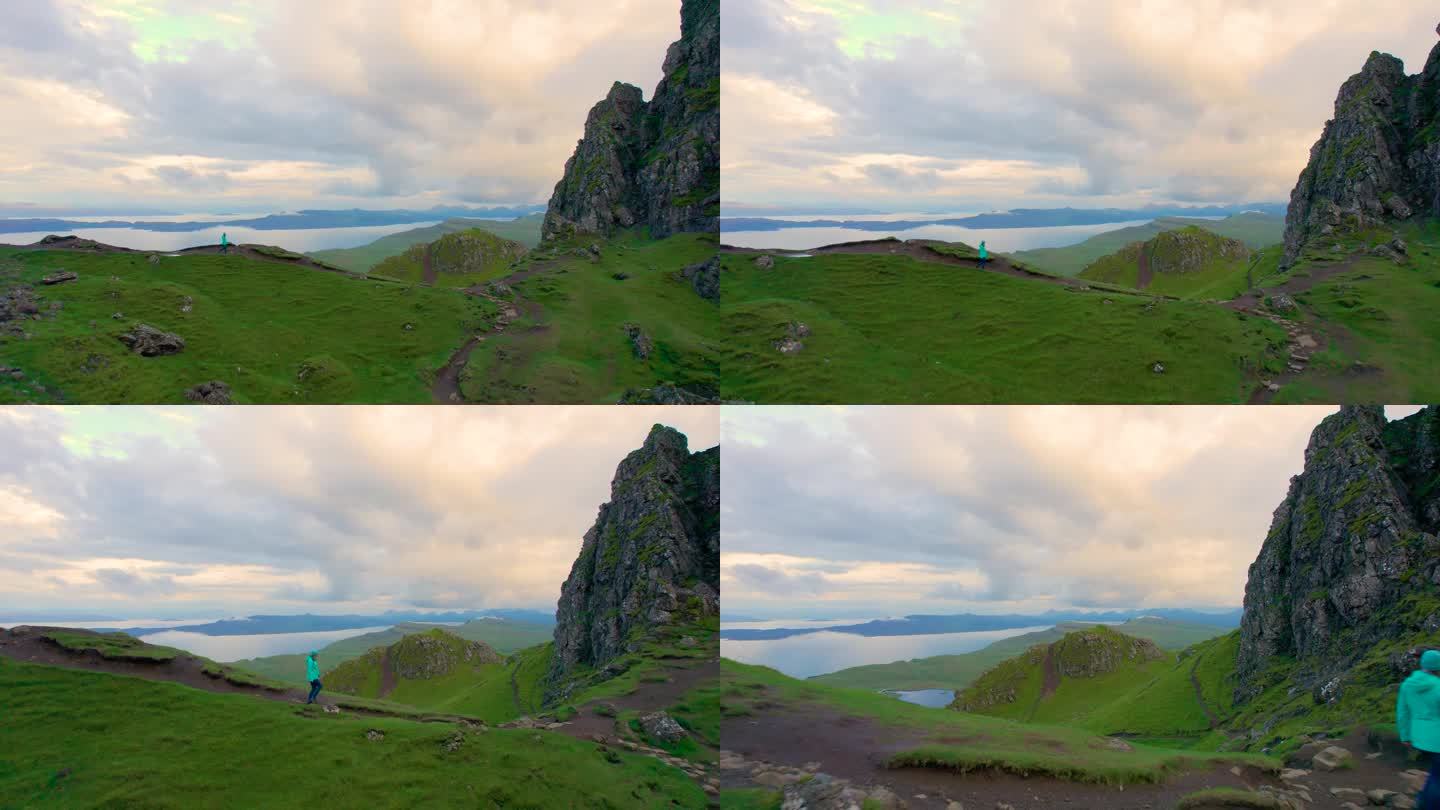 航拍:年轻的女士沿着山脊散步，俯瞰着令人惊叹的苏格兰风景