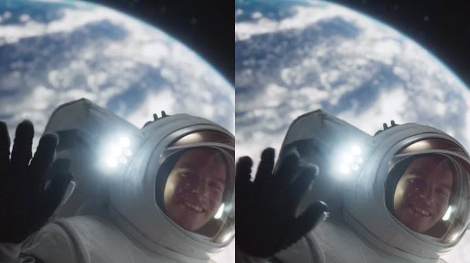 垂直屏幕:一名宇航员漂浮在宇宙飞船外的肖像，背景是地球。男:对着镜头挥手。职业太空人穿着太空服，微笑