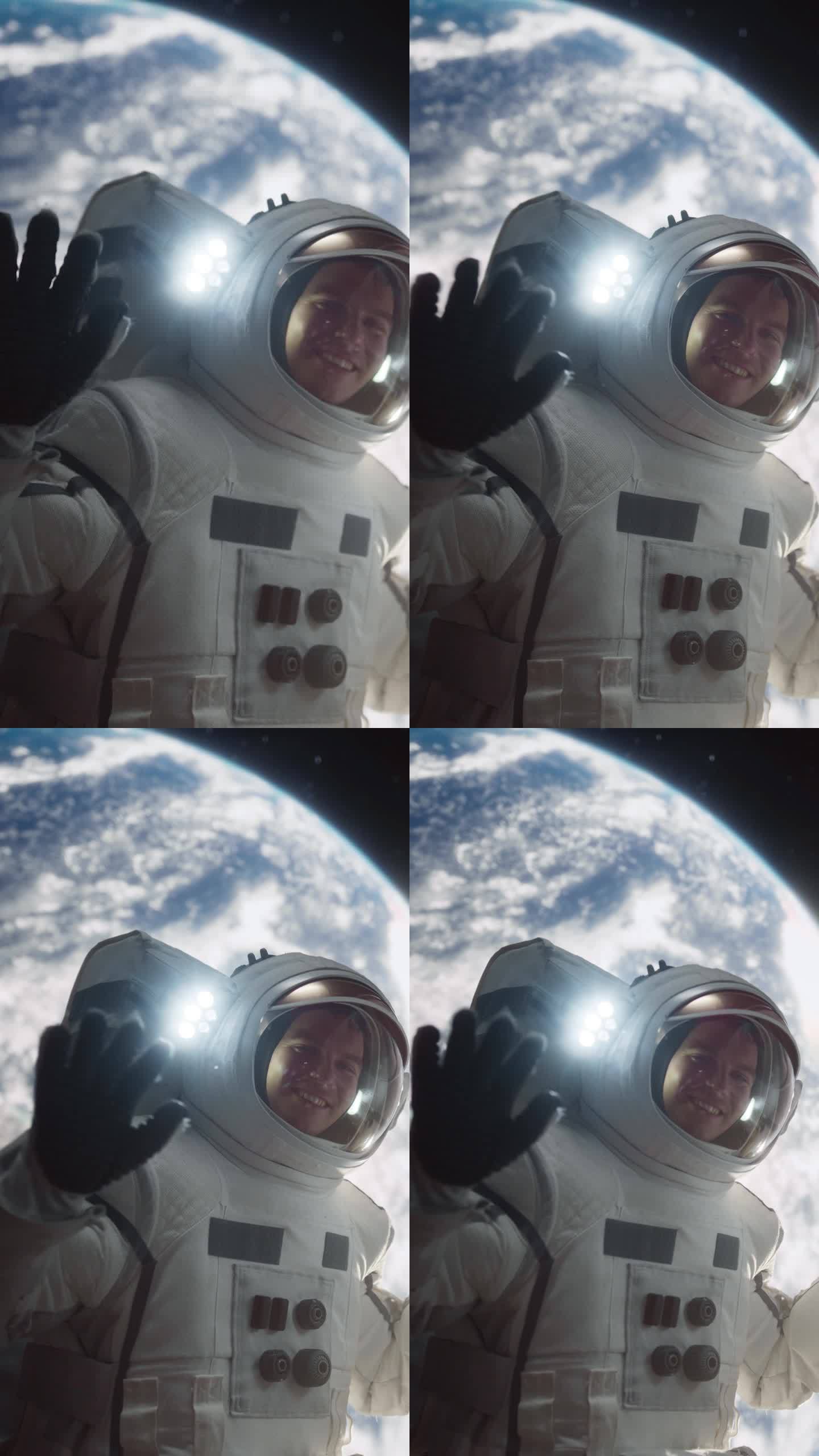 垂直屏幕:一名宇航员漂浮在宇宙飞船外的肖像，背景是地球。男:对着镜头挥手。职业太空人穿着太空服，微笑