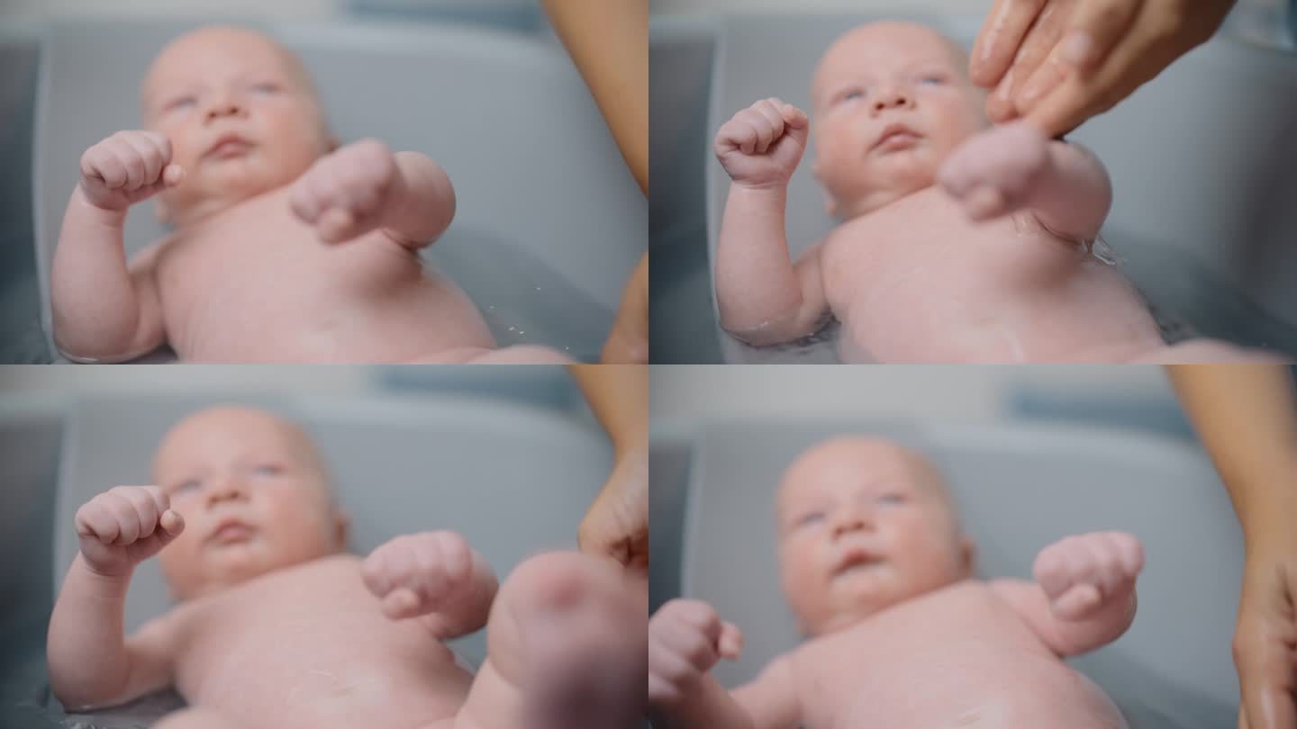 在家里的浴缸里，妈妈的手把水滴在小男孩的肚子上