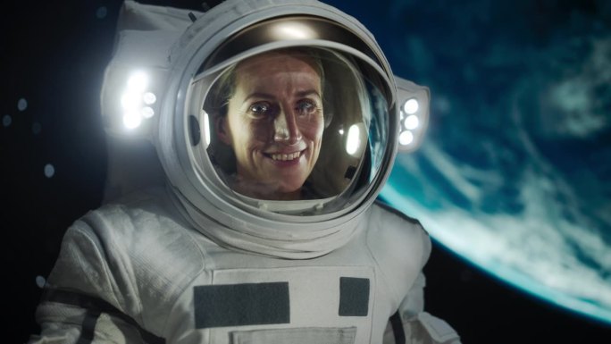 在空间站、卫星或宇宙飞船外太空行走时，一名女宇航员穿着宇航服摆姿势的肖像。欢快的女宇航员看着镜头微笑