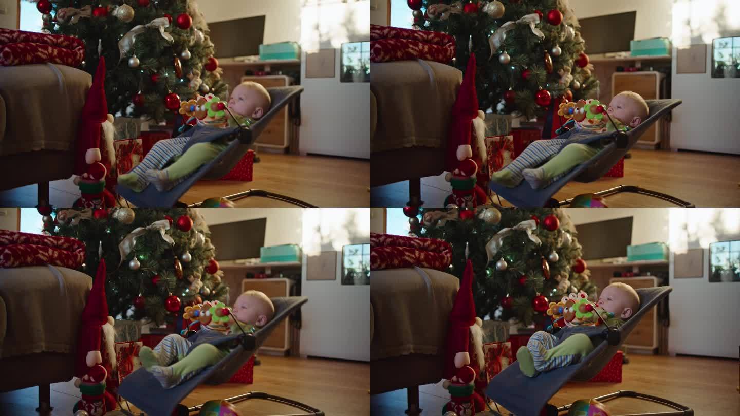 在家里客厅装饰的圣诞树旁，小男孩在Bouncer上玩耍的慢镜头