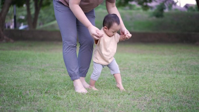 母亲在公园里训练她的儿子，让他学会迈出第一步
