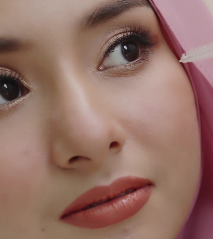 特写一个美丽的亚洲穆斯林妇女的笑脸，用头巾遮住她的美丽。美丽的穆斯林女孩睁开眼睛。