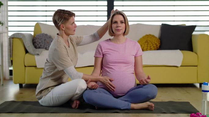 孕妇在家跟教练练瑜伽。