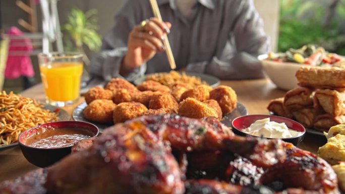 餐桌上的新鲜亚洲美食。以东方产品为原料的亚洲烹饪概念。女人坐着吃起司丸子和竹签炒面