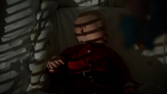 正上方手持拍摄的顽皮的男婴躺在婴儿床在暗房白天