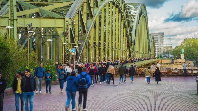 德国科隆，拥挤的人群和游客走在霍亨索伦桥的人行桥上，这座桥是莱茵河上标志性的铁路，成千上万的挂锁象征