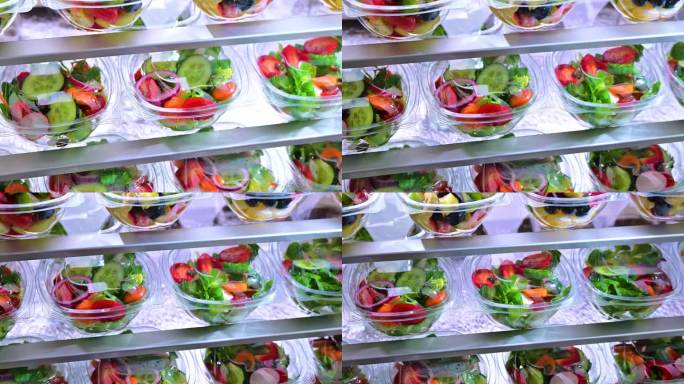 塑料盒子里装着预先包装好的水果和蔬菜沙拉，在商用冰箱里出售